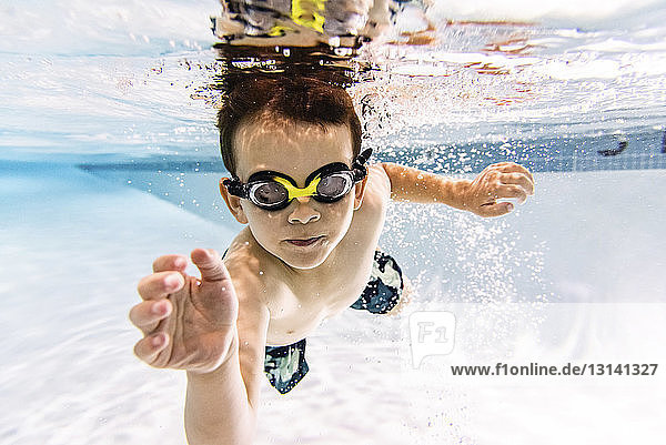 Porträt eines Jungen ohne Hemd  der im Schwimmbad unter Wasser schwimmt