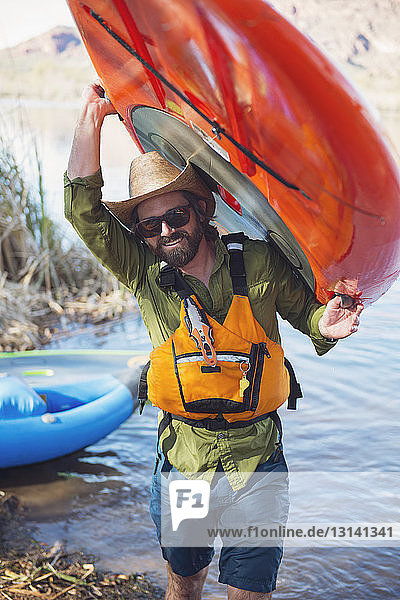 Porträt eines glücklichen Mannes mit Paddelbrett am Seeufer