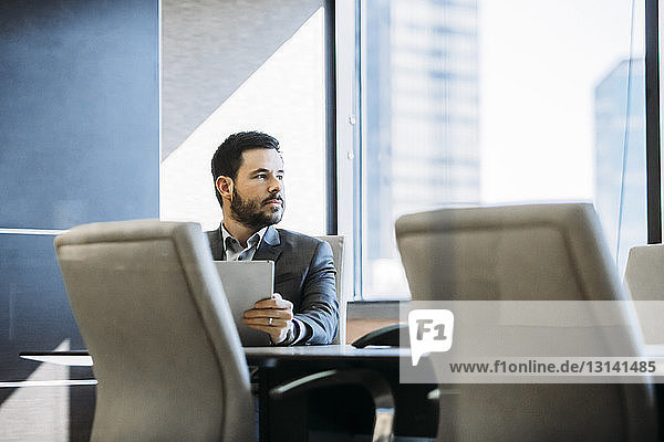 Nachdenklicher Geschäftsmann schaut weg  während er im Sitzungssaal sitzt