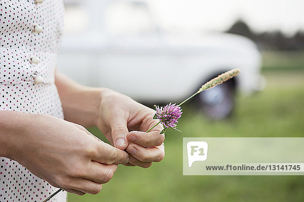 Nahaufnahme einer Frau  die Blumen hält  während sie auf einem Grasfeld steht
