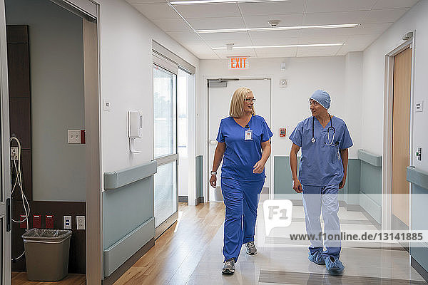 Chirurg und Krankenschwester sprechen während des Gehens im Krankenhauskorridor