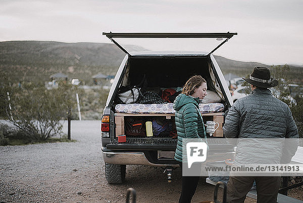 Freunde unterhalten sich  während sie im Red Rock Canyon National Conservation Area bei einem Geländewagen stehen