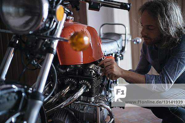 Mann untersucht Motorrad in Werkstatt