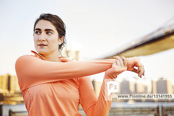 Entschlossene Sportlerin streckt Arm gegen Brooklyn Bridge