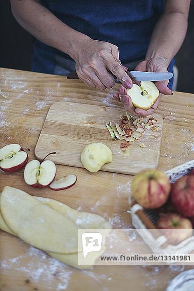 Geschnittene Hände einer Frau  die Äpfel für die Zubereitung von Zimtbrötchen zu Hause schneidet