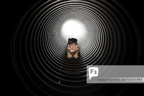 Portrait of playful boy lying in huge metallic pipe