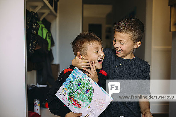 Fröhlicher Junge hält beim Heimspiel das Gesicht seines Bruders