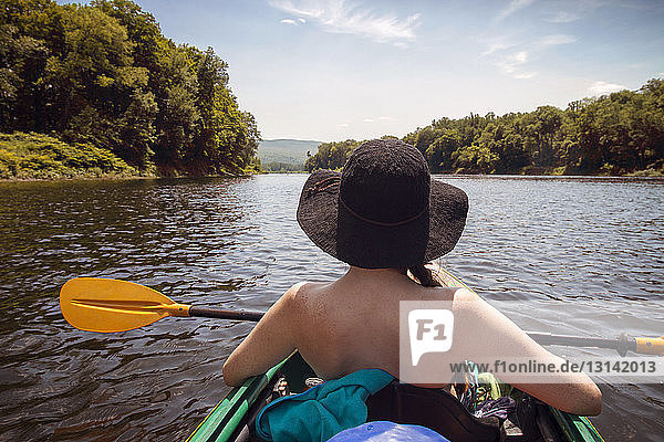 Rear view of woman kayaking in lake at forest