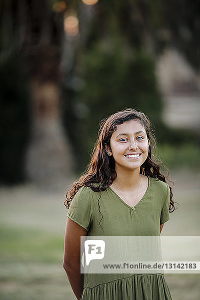 Portrait of cheerful girl standing at park