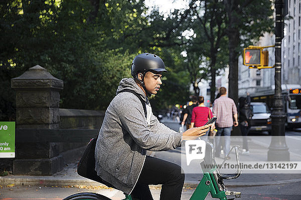 Mann mit Fahrrad mit Mobiltelefon auf Stadtstraße