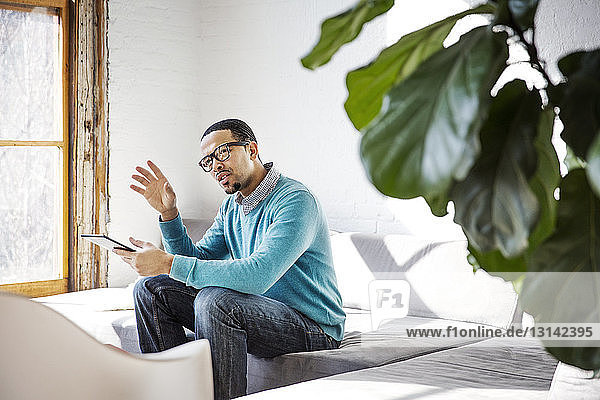 Businessman gesturing while sitting on sofa in office