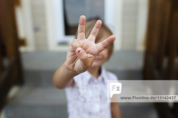 Mädchen zeigt drei Finger beim Stehen auf Stufen