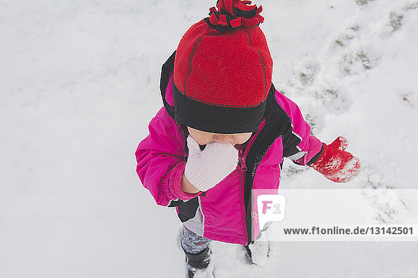 Hochwinkelaufnahme eines Mädchens  das auf einem verschneiten Feld steht
