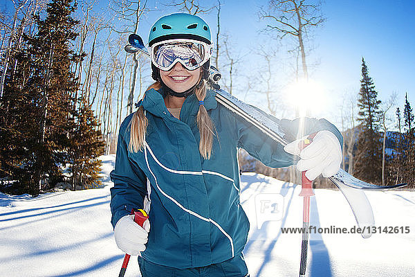 Happy woman with skis on snow covered mountain during sunny day