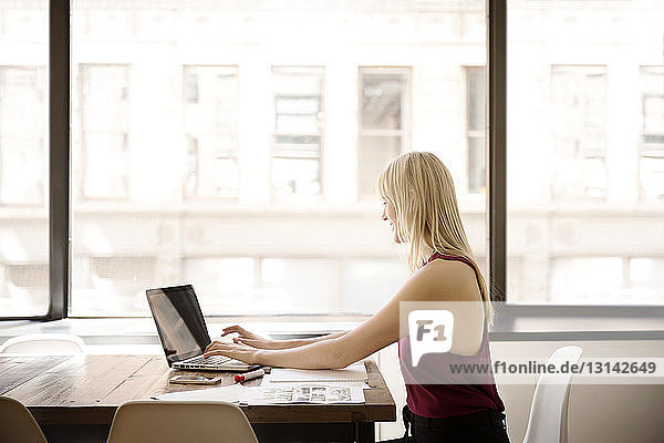 Seitenansicht einer Geschäftsfrau mit Laptop im Kreativbüro