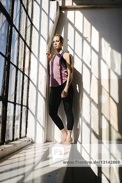 Portrait of athlete standing by window in gym