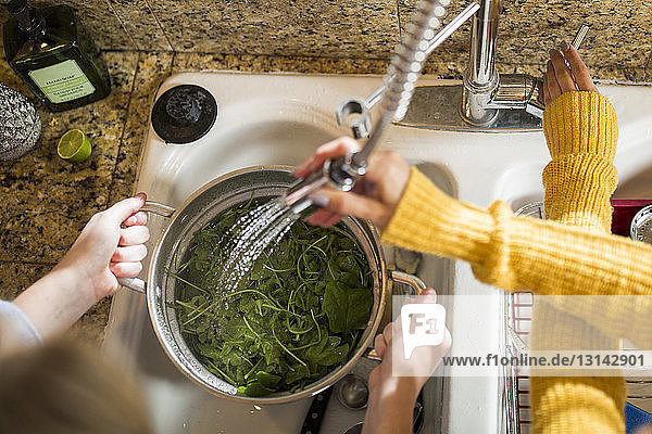 Ausgeschnittenes Bild von Händen  die Gemüse an der Küchenspüle waschen