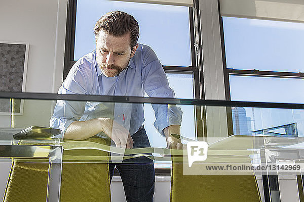 Low angle view of businessman analyzing photographs at glass conference table in creative office