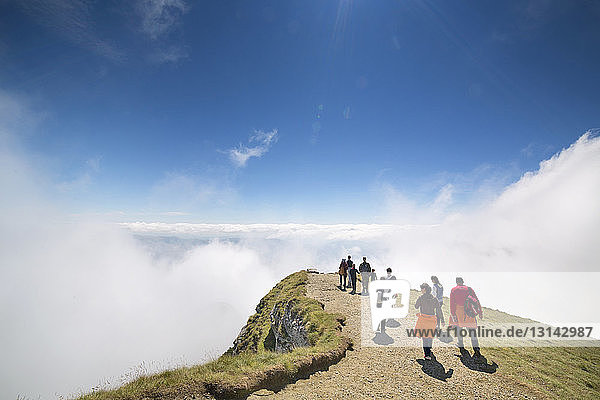 Hikers walking on cliff surrounded by clouds