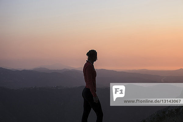 Seitenansicht einer Frau  die bei einem Spaziergang auf einem Berg vor klarem Himmel die Aussicht betrachtet