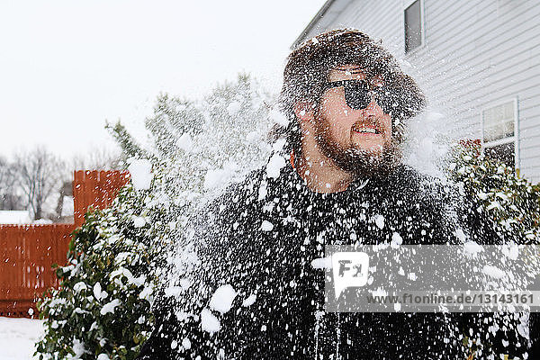 Schneefall auf vor dem Haus stehenden jungen Mann