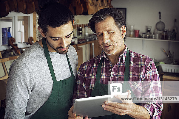 Man showing tablet computer to coworker while standing in workshop