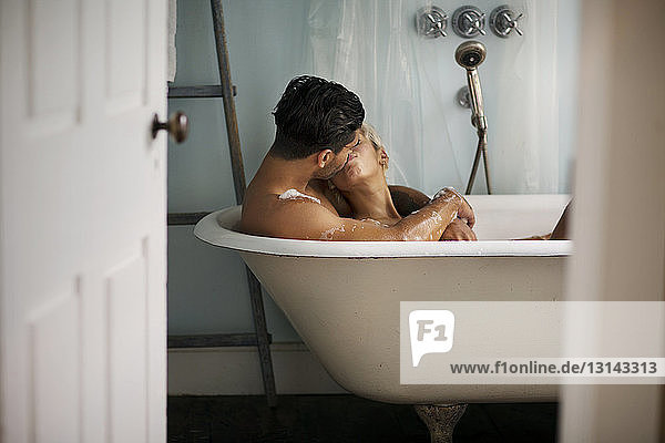 Junges Paar küsst sich zu Hause in der Badewanne