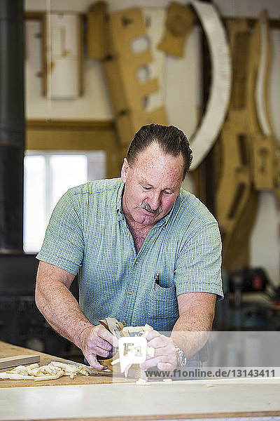 Zimmermann schnitzt Holz während der Arbeit in der Werkstatt