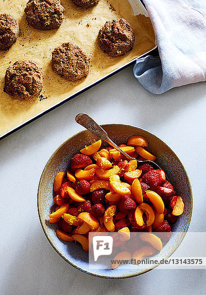 Draufsicht auf Pfirsichscheiben und Erdbeeren in einem Behälter mit Keksen auf weißem Hintergrund