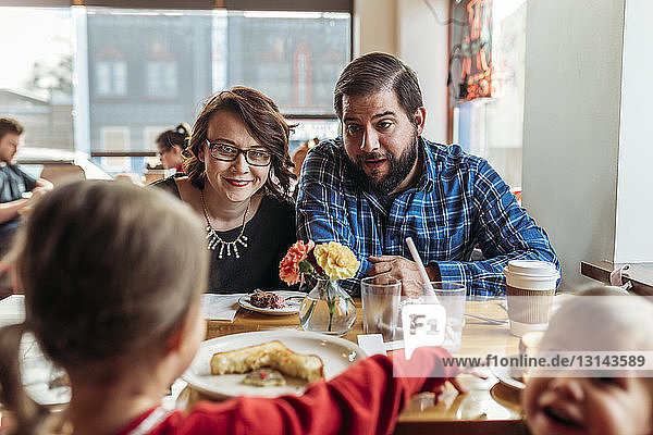 Parents talking to girl while sitting at restaurant table