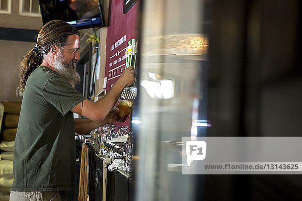 Side view of bartender pouring beer from tap