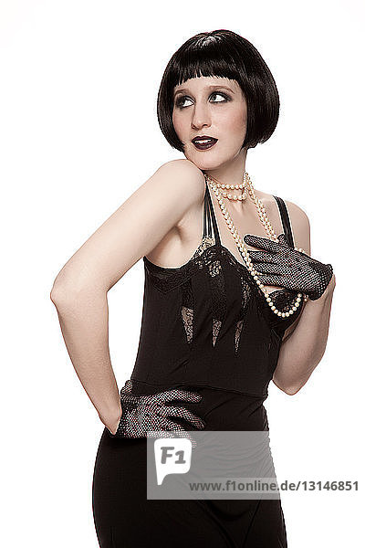 Mid adult woman in 1920's style black dress against white background
