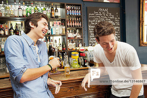 Smiling men drinking beers in bar