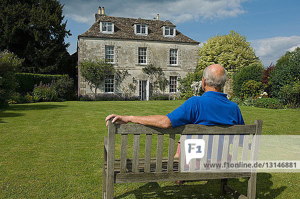 Älterer Mann sitzt im Hinterhof