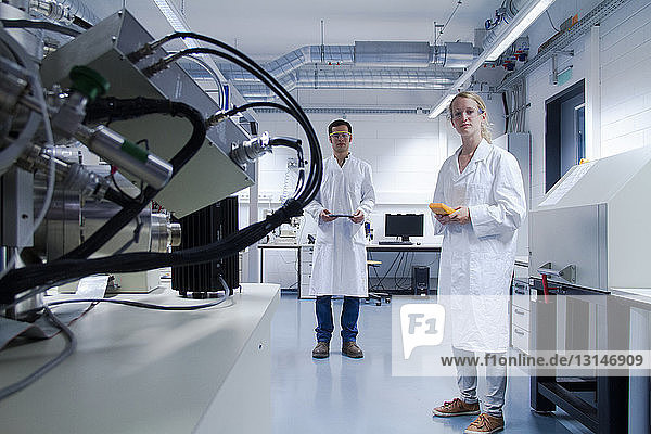 Zwei Wissenschaftler in Laborkitteln und mit Schutzbrille stehen in einem Labor