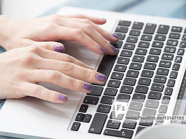 Young woman typing on laptop keyboard  focus on hands