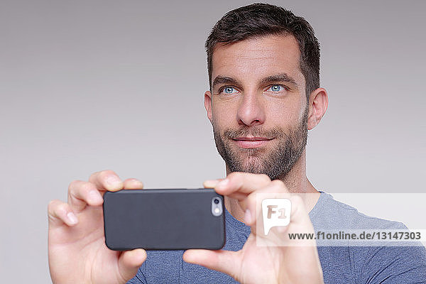 Mittelgroßer erwachsener Mann  fotografierend  mit Smartphone