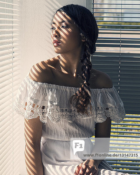 Porträt einer jungen Frau  sitzend am Fenster  in weißem Kleid