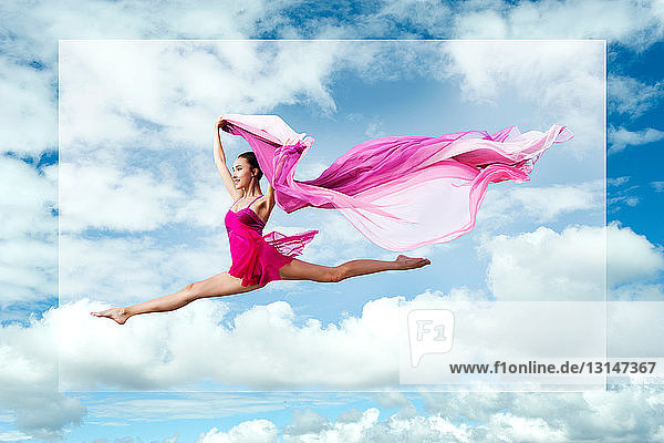 Ballerina springt gegen bewölkten Himmel