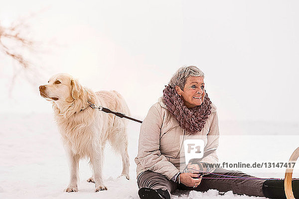 Woman sitting on snow with dog