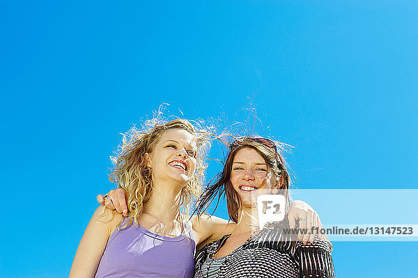 Portrait of two girls against blue sky