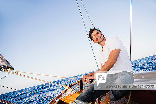 Mann steuert ein Segelboot