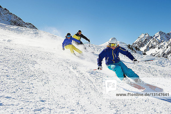 Three skiers going downhill