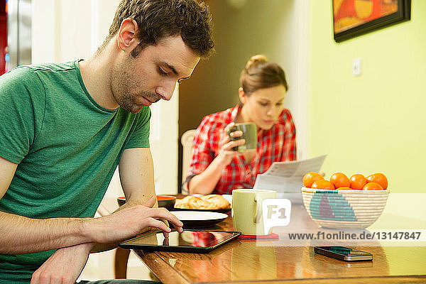 Young couple at breakfast  man using digital tablet