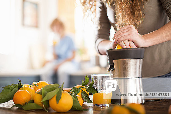 Teenager-Mädchen entsaften Orange in der Küche