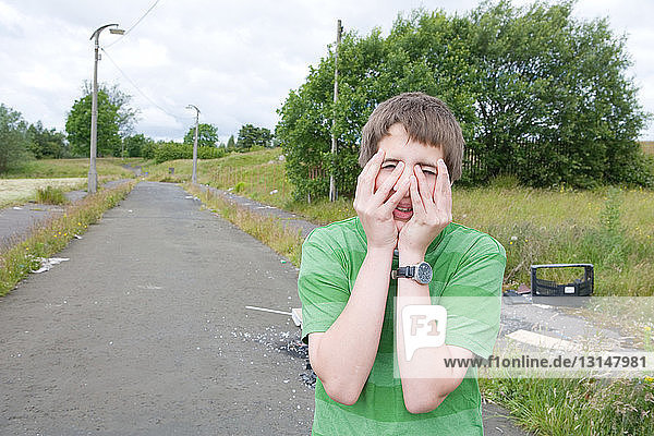 Teenage boy covering face with hands