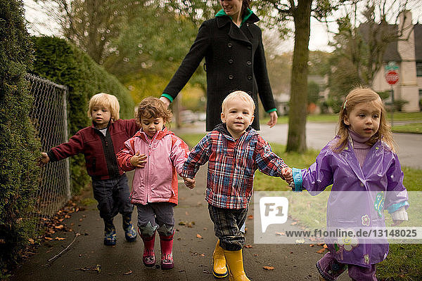 Woman with four children walking along pavement