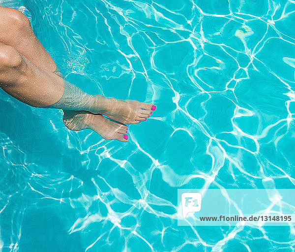 Frau badet Füße im Schwimmbad