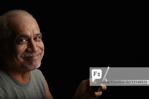 Lächelnder älterer Mann  der ein Mobiltelefon benutzt