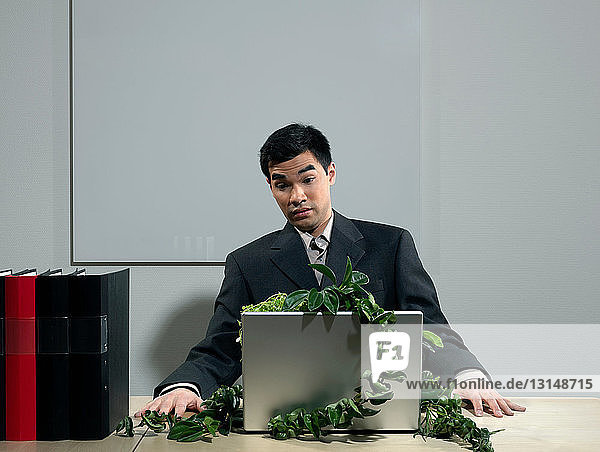 Man by desk beeing attacked by plants